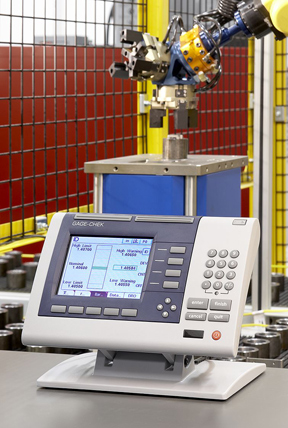 Measuring the inside diameter of a bushing after the frst machining operation. A robot arm has placed the workpiece in the gaging fxture (the blue box). The gage amplifer in the foreground shows the ID measurement Measuring the inside diameter of a bushing after the first machining operation. A robot arm has placed the workpiece in the gaging fxture (the blue box). The gage amplifer in the foreground shows the ID measurement
