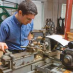 Intern Ben Holleran demonstrates a turret lathe made by Pratt and Whitney Co., Hartford, Conn.