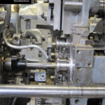 A multi-blade cutoff saw installed on a Davenport screw machine at Waterbury Screw Machine Products Company.