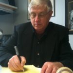 Lloyd Graff writing at his desk at Graff Pinkert Co. in Oak Forest. Ill.